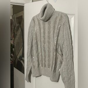 This stylish piece is a gray cable-knit turtleneck sweater